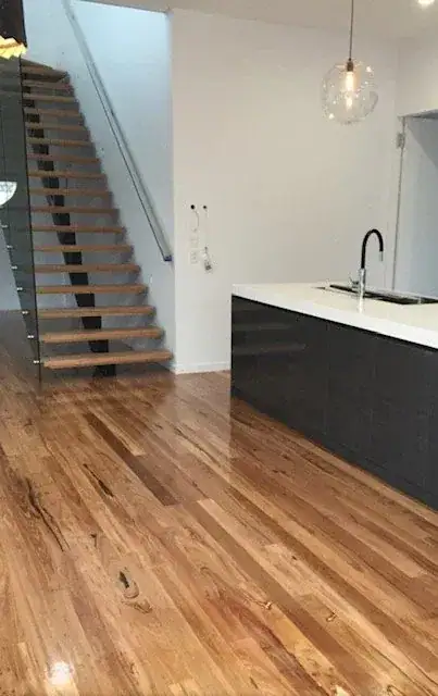 A polished hardwood floor by an open staircase
