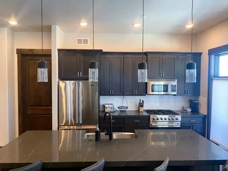 A clean vacation rental kitchen with dark cabinets and a stone island in Central Oregon