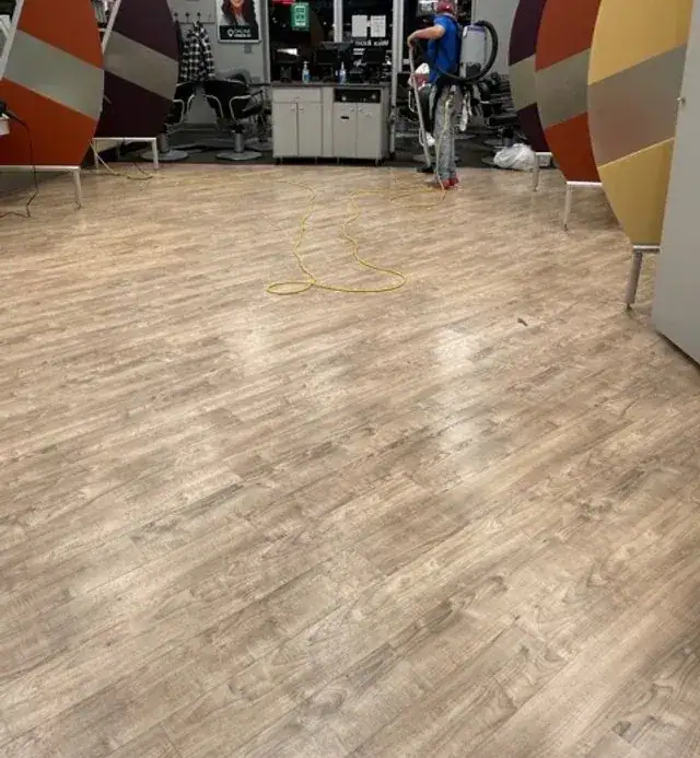 A salon floor being cleaned by a Central Natural Cleaning crew member