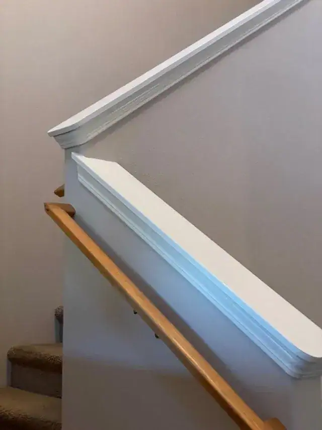 A white stair railing and wood handrail dusted during a deep cleaning