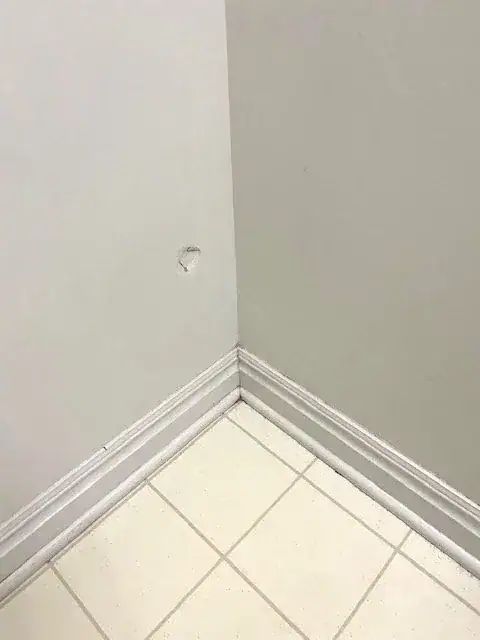 The same tile floor corner after scrubbing, tile and baseboard clean