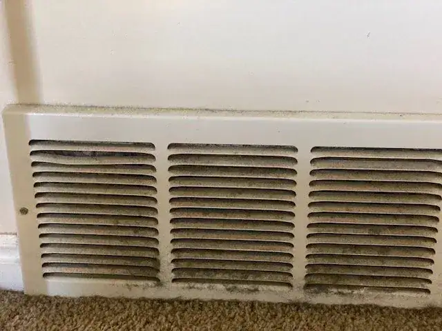 A dusty floor vent before a deep cleaning